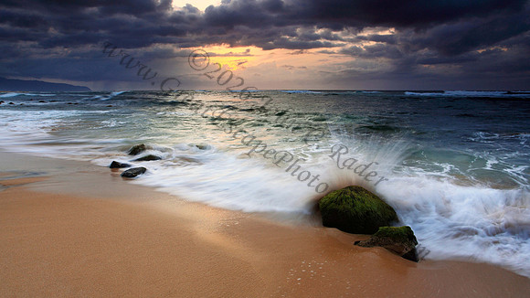Small waves crash over an algae covered rock somewhere on North Shore, Oahu Hawaii
