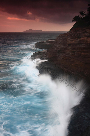 Waves crash on cliffs spitting caves explosions sunset splashing Oahu Hawaii