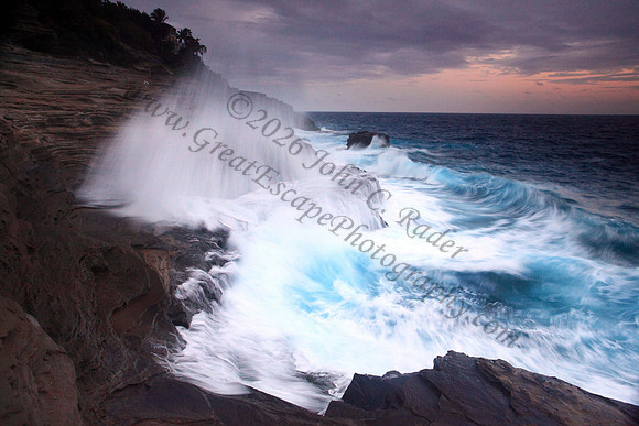 Waves crash on cliffs spitting caves explosions sunset splashing Oahu Hawaii