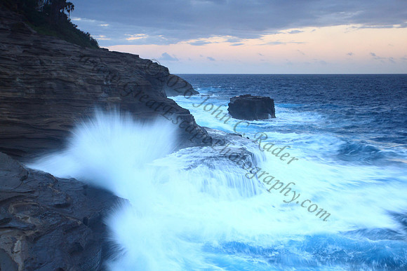 Waves crash on cliffs spitting caves explosions sunset splashing Oahu Hawaii